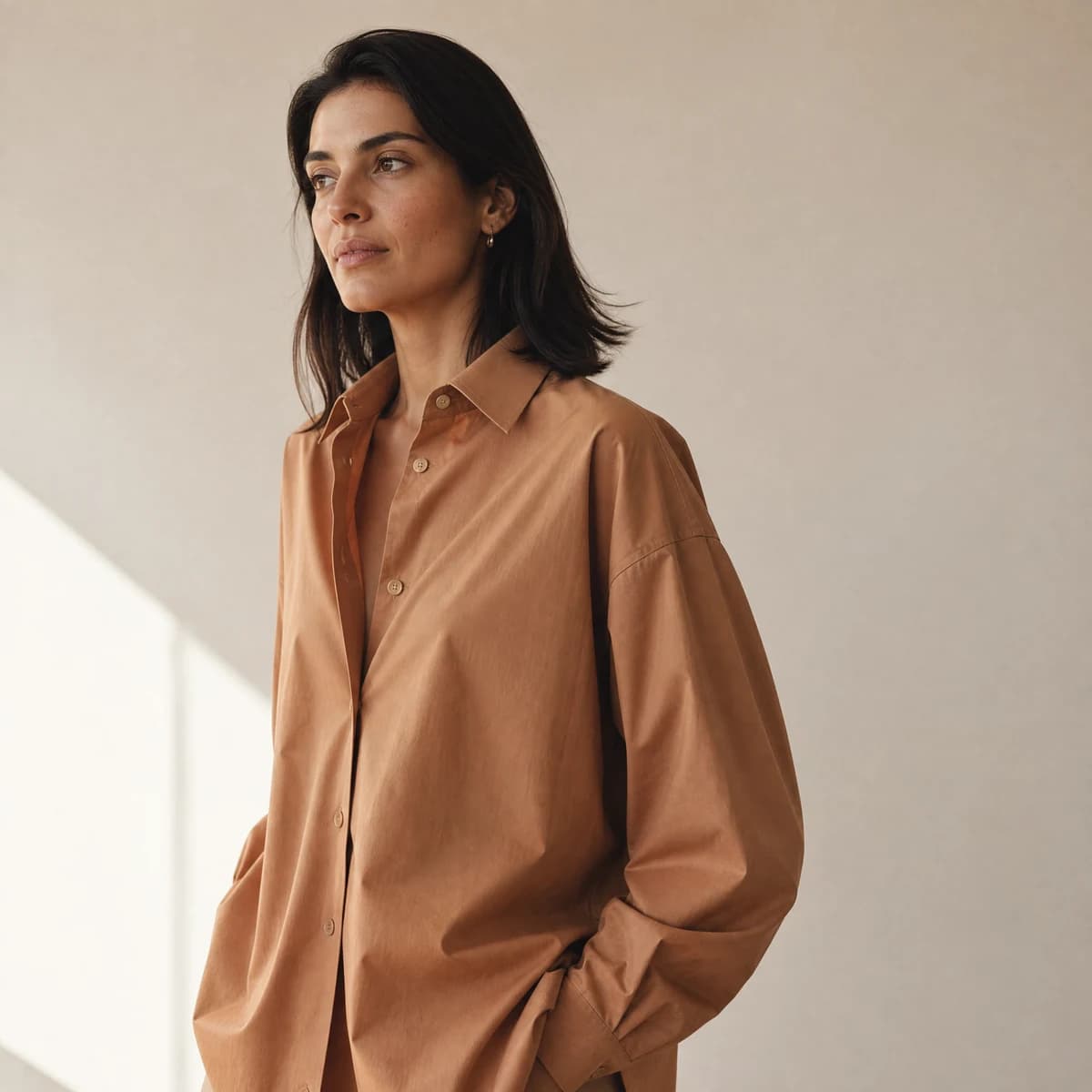 Camisa oversized caramel mostrando ombro caído e drape generoso.