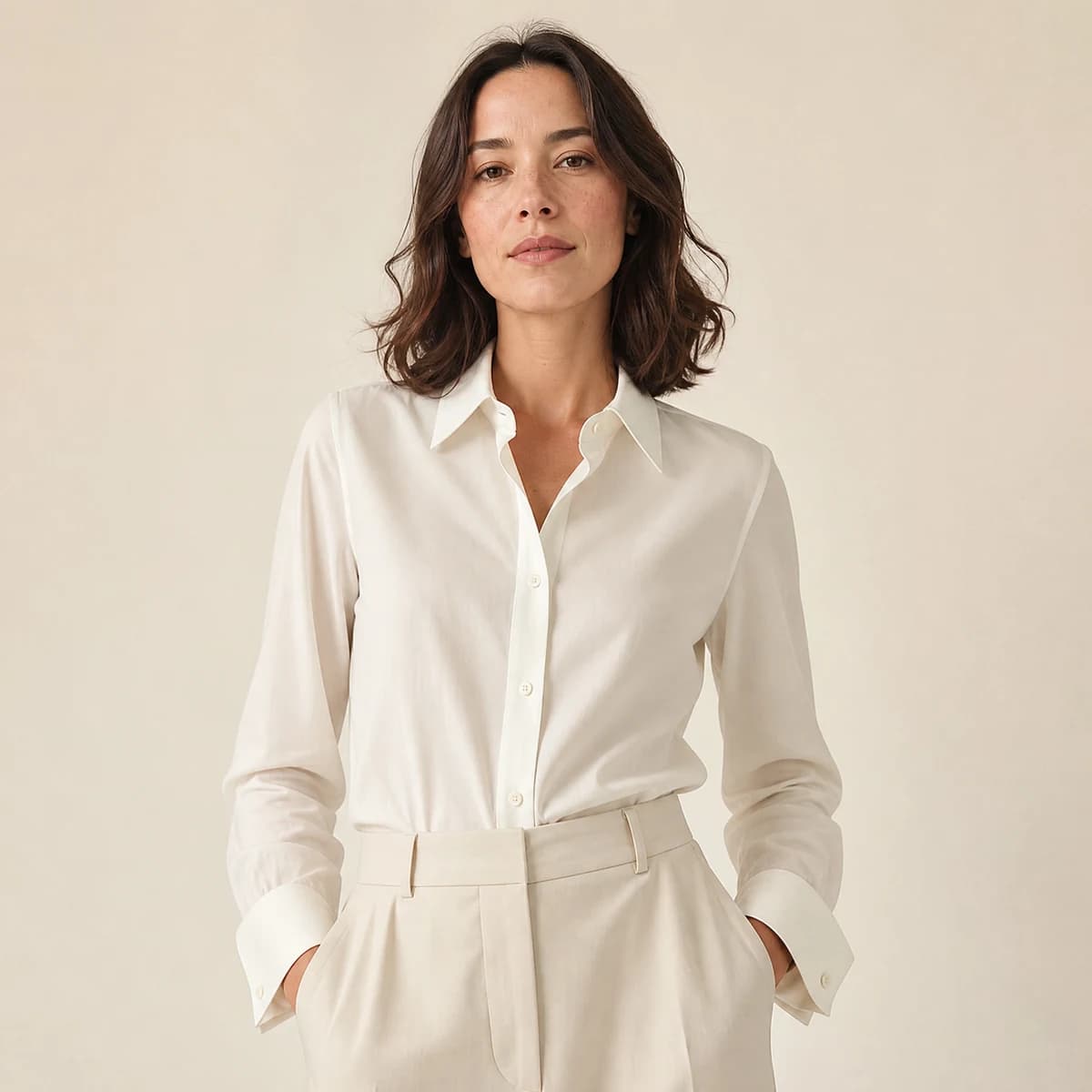 Camisa tradicional off-white com punho duplo, presença editorial frontal.